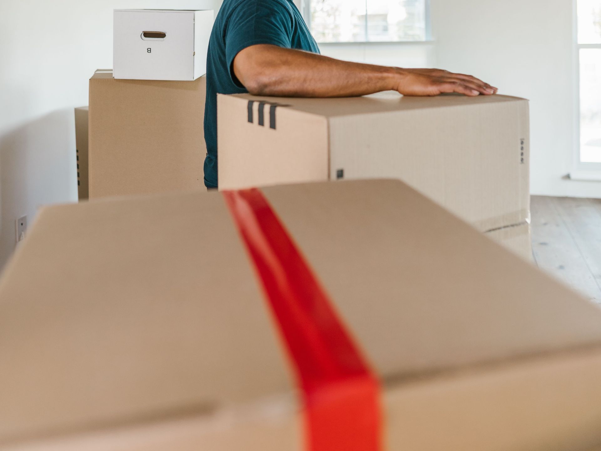 Man handling moving boxes in a spacious, modern room during relocation.